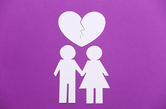 Paper man and woman with a red broken heart on a purple background.