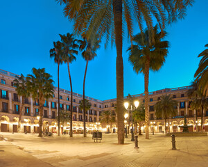 Fototapeta na wymiar Barcelona at night in golden light and blue. Panoramic image of illuminated Plaza Real in in Gothic quarter of Barcelona, Catalonia, Spain