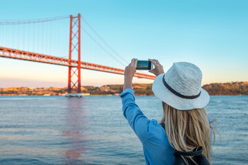 Young traveler woman with smartphone takes pictures in Lisbon 