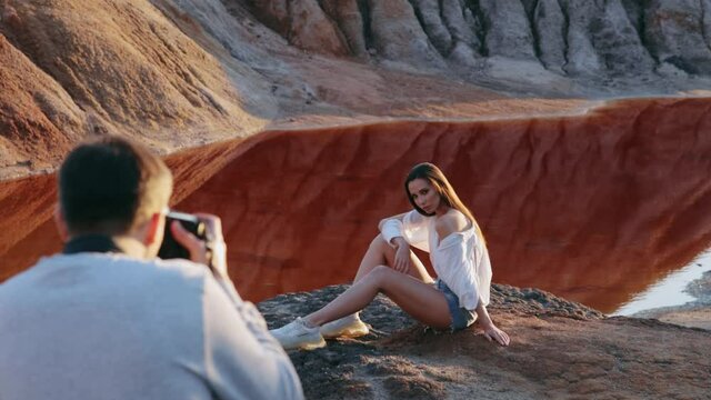 Photographer taking pictures of beautiful woman on other-worldly hilly landscape