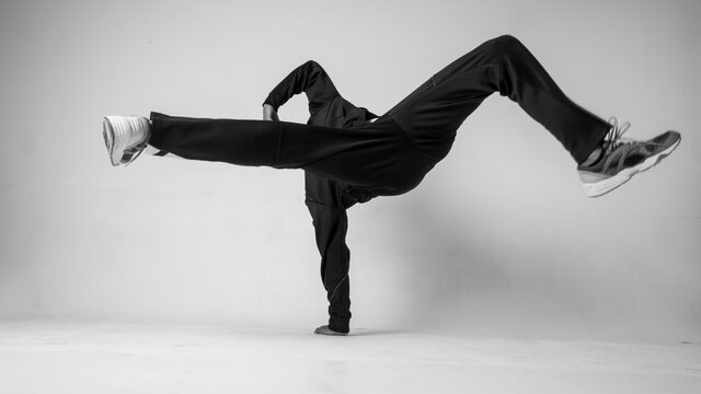 A man hip hop dancer or bboy freezes in one pose on a white background. Bboy doing stylish stunts.