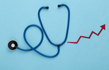 Stethoscope with growth arrow on blue background. Top view
