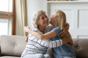 Aged mother and grown up adult daughter embracing seated on couch. Miss each other, not forget visit elderly parents, showing care express attention, caring offspring and older generation love concept