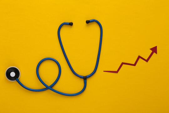 Stethoscope with growth arrow on yellow background. Top view