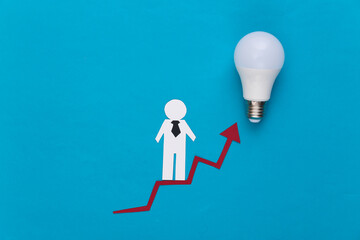 The concept of career and social growth. Paper man on a rising arrow with a light bulb. Blue background.
