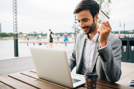 Young Man Holding Credit Card And Typing On A Computer