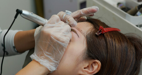 Obraz na płótnie Canvas Woman undergo eyebrow microblading, permanent makeup