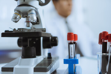 Young Asian man scientist in background use Microscope to looking biochemical cell in laboratory. Doctor and scientist work in laboratory pandemic of corona virus, COVID19 concept