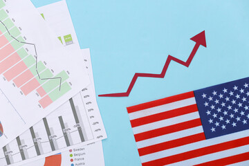 Fototapeta premium Growth upward arrow, graphs and charts, USA flag on blue background. Economic success. Top view