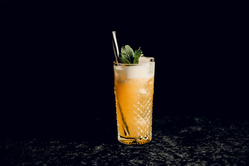 Orange cocktail with mint in a beautiful glass with ice on a dark background