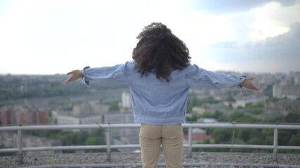 Teenager enjoying view of city, raising hands up, feeling inspired, adolescence