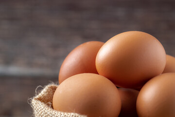 Close-up view of raw eggs in egg Sack on Brown wooden background