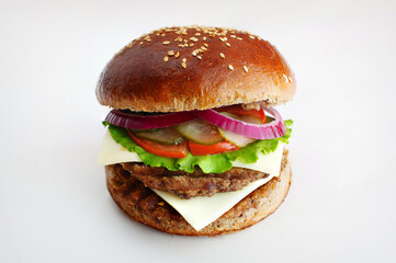 Juicy burger from dark flour with onion rings, cucumbers, lettuce, cheese on a white background