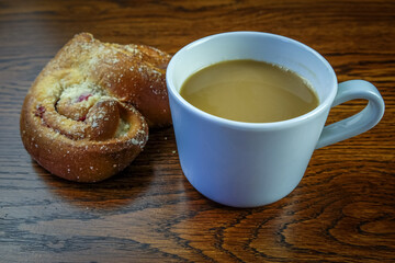 cup of coffe and a bun on a wooden background