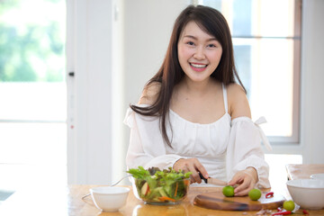 Obraz na płótnie Canvas Beautiful Asian women, beautiful smile, good health, beautiful teeth, eating salad vegetable when working at home.