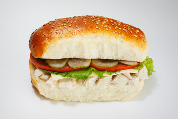 Juicy sandwich with cucumbers, lettuce, cheese and chicken on a white background