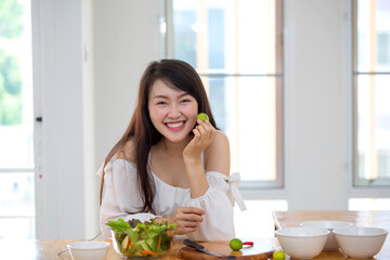 Obraz na płótnie Canvas Beautiful Asian women, beautiful smile, good health, beautiful teeth, eating salad vegetable when working at home.