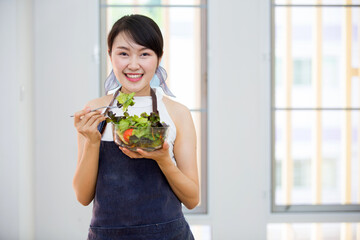 Beautiful Asian women, beautiful smile, good health, beautiful teeth, eating salad vegetable when working at home.