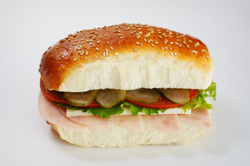 Juicy sandwich with cucumbers, lettuce, cheese and ham on a white background