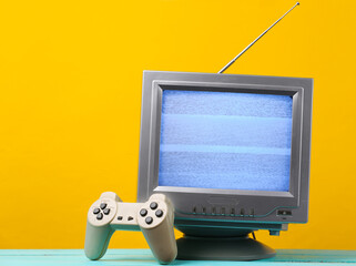 Antenna old-fashioned retro tv receiver with gamepad on yellow background. Retro entertainment 80s