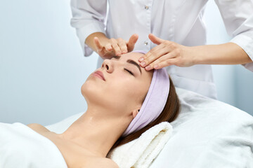 beautiful woman receiving facial massage in a beauty clinic.