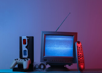 Retro media, entertainment 80s. Antenna old-fashioned tv receiver, anaglyph glasses, clock, audio and video cassette, gamepad, remote in pink blue gradient neon light. Retro wave