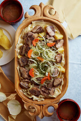 Nationally Kazakh dish beshbarkak in wooden utensils. On white table. Close-up