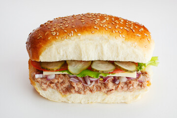 Juicy sandwich with cucumbers, lettuce, cheese, onion and tuna on a white background