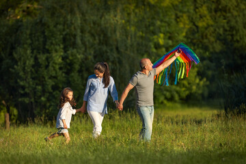 happy family with cute child girl launches kite in sunny summer day.
