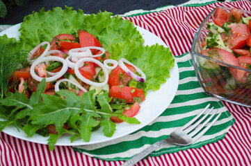 Salad with juicy tomatoes, lettuce, cucumber, red onion, arugula, dill and fresh parsley. Homemade food. The symbolic image. The concept of tasty and healthy vegetarian food. Top view and side view. 