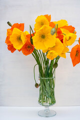 Yellow and orange poppies in a glass vase.