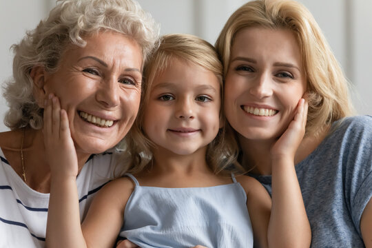 Close up concept image beautiful faces or 3 generations multi-generational relatives women portrait. Little granddaughter pose between old grandmother and young mother family smiling looking at camera