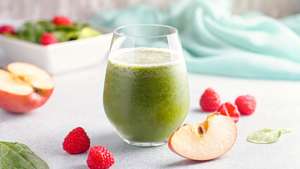 Glass with green smoothie with reusable drinking straws with spinach, raspberry and apple on...