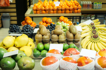 Nutritional organic fruits on supermarket shelf. Colorful kiwi, bananas, tangerines, grapes and limes in grocery. Healthful food, healthy eating, dieting, vitamins.