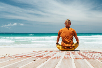 The view from the back, the place of meditation, guy sits on the shore of a tropical beach during...