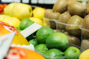 Green limes on shelf with blurred kiwi and pears at the background. Healthy vitamin eating, organic food, fruits in grocery..