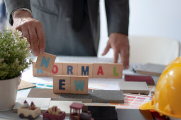 Work frome home concept. Architect select new normal text design on work table.