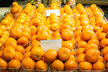 Lot of tangerines in baskets on shelf in grocery. Organic vitamin fruits on supermarket shelf. Dieting, vegan food, healthy eating.