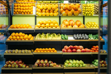Wide shot of healthful fruits on grocery shelves. Multi-colored apples, pomegranates. tangerines, bananas and avocados in supermarket. Healthy eating, dieting, vitamin food.