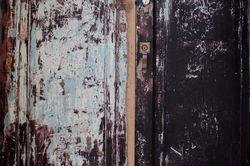 Old used scratched wooden door background with marks chipped old paint white maroon red, light blue, black natural colors, beautiful background
