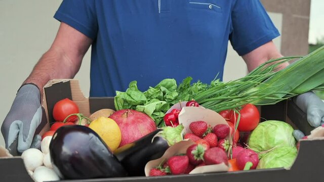 Delivery Man Wearing Blue T-shirt And Black Mask Giving To A Woman Black Fruit And Vegetables Box During Covid-19 Pandemic, Slow Motion