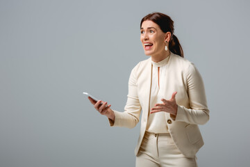 Angry businesswoman holding smartphone isolated on grey, concept of body positive