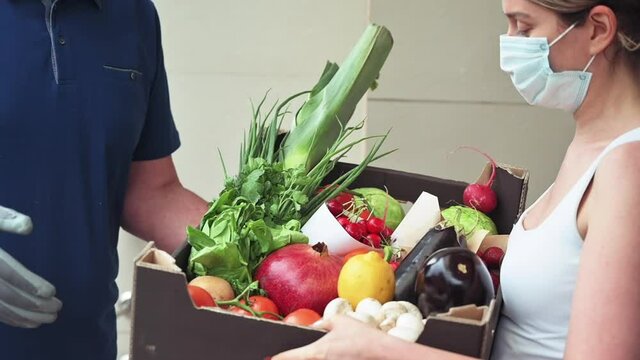 Delivery Man Wearing Blue T-shirt And Black Mask Giving To A Woman Black Fruit And Vegetables Box During Covid-19 Pandemic, Slow Motion