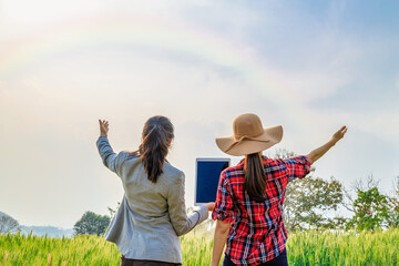 asian business and farmers women holding hand and tablet on hand in barley agricultural farmland