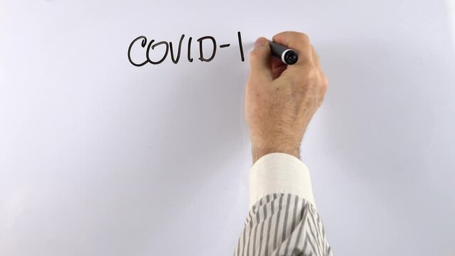 Lecturer writes information on covid-19 and dexamethasone on a whiteboard