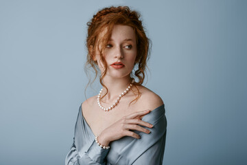 Beautiful elegant redhead freckled woman wearing luxury pearl jewelry set: necklace, bracelet, silk...
