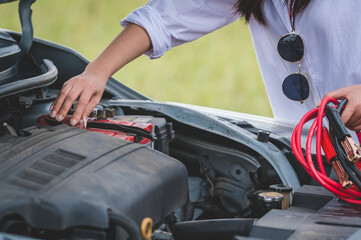 Closeup of woman hand holding battery cable copper wire for repairing broken car