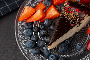 Piece of cheesecake with chocolate top and berries
