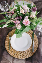 Table setting for a romantic dinner. Beautiful flowers in a vase on the table
