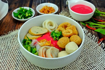 Flat rice noodle with assorted fish balls in red tofu “Yentafo” sauce served with side dishes.